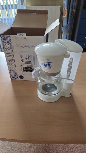 Kleine koffiepot wit met blauw embleem.