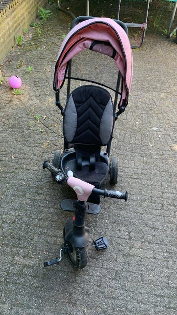Roze driewieler met duwstang en zonnekap