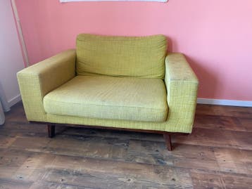 Gele fauteuil met beschadigd pootje