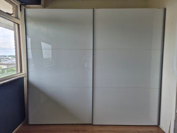 Witte kledingkast met schuifdeuren. Merk onbekend.