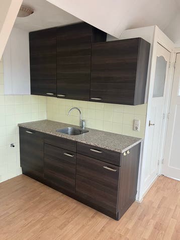 Compacte keuken met donkerbruine kasten en granieten blad