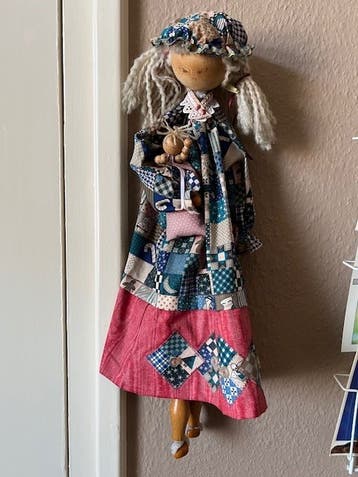 Zelfgemaakte houten pop met kind en kleding voor aan de muur