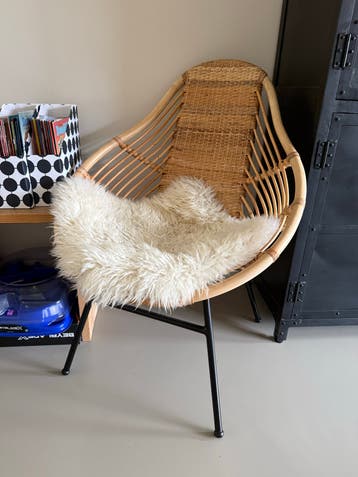 Rotan stoel met metalen onderstel en schapenvacht