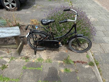 Zwarte kinderfiets met bagagedrager en mandje