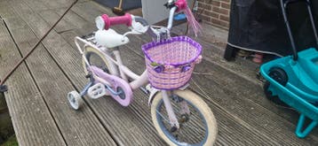 Roze kinderfiets met zijwieltjes en mandje