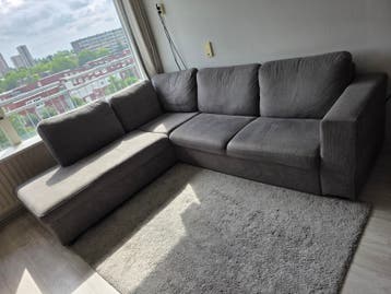 Grijze hoekbank met lichte gebruikssporen en kattenkrassen