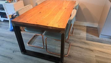 Robuuste eettafel met metalen onderstel en 4 groene stoelen.
