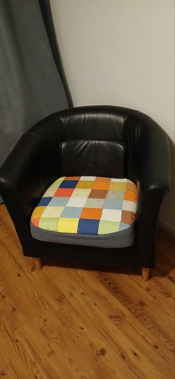 Zwarte leren fauteuil met kleurrijk kussen