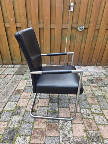 Vier zwarte leren eetkamerstoelen met metalen frame