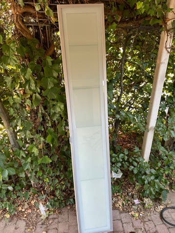 Hoge smalle kast met glazen planken en deur