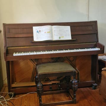 Piano met gebruikssporen, onbekend merk, op wieltjes