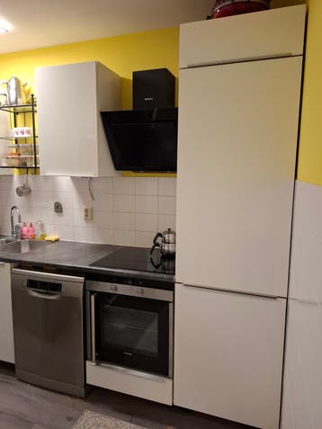 Moderne hoekkeuken met inbouwapparatuur en greeploze kasten