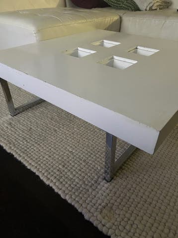 Witte salontafel met metalen poten en vierkante uitsparingen