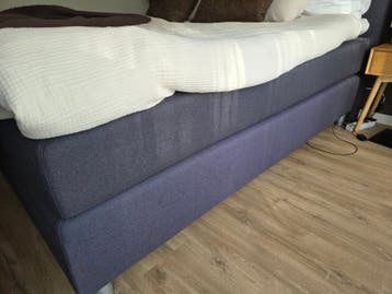 Tweepersoons boxspring met beschadigd hoofdbord