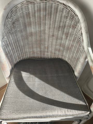 Witte rotan stoel met grijs kussen