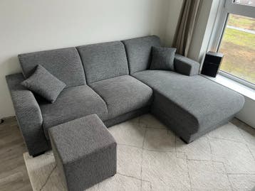 Grijze 3 zitsbank met chaise longue en poef
